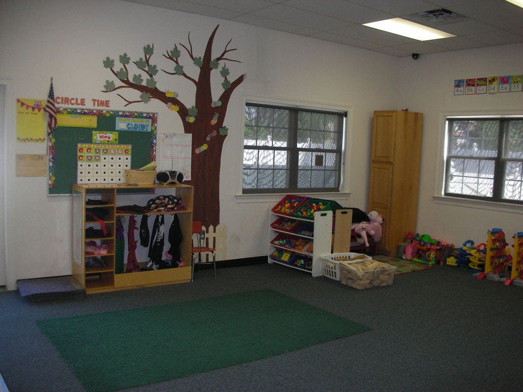 Empty classroom with a tree mural, bulletin board, and toy shelves