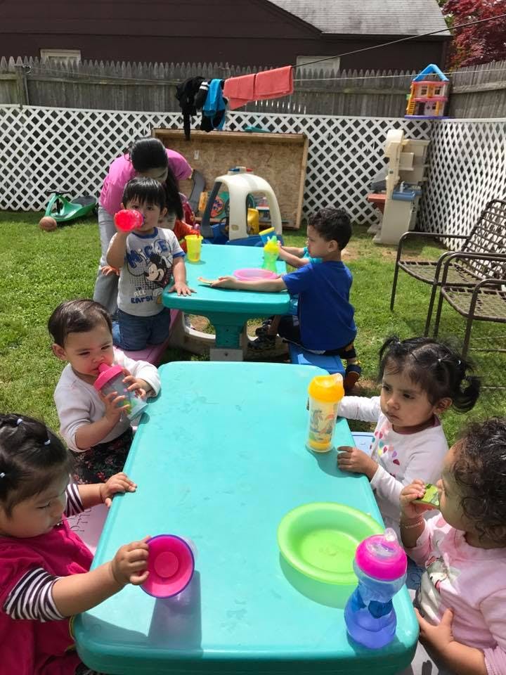 Children and an adult at small tables outdoors