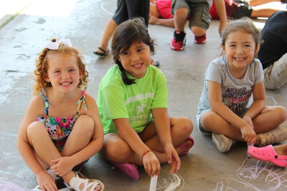Three children sitting on the ground