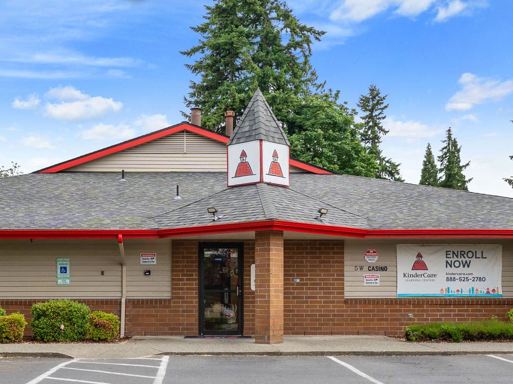 Exterior of a KinderCare Learning Center building with an "Enroll Now" banner