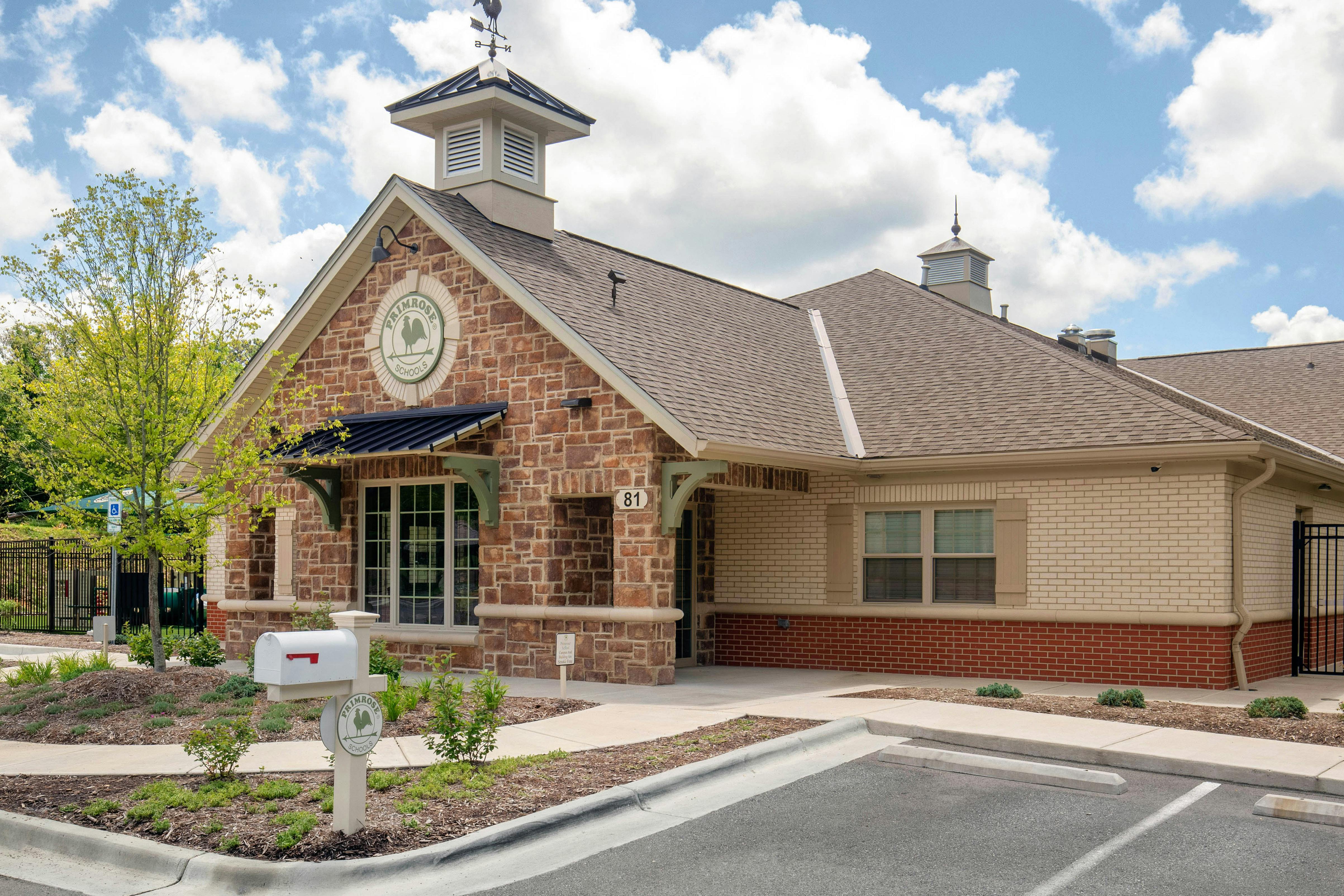 A school building with stone and brick exterior, a weathervane, and a mailbox