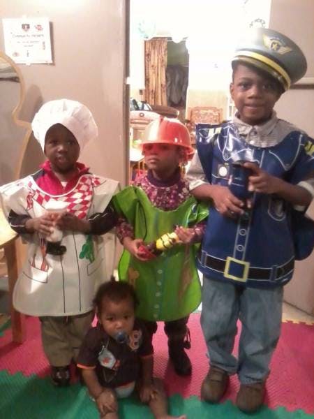Three children in costumes and one baby on the floor