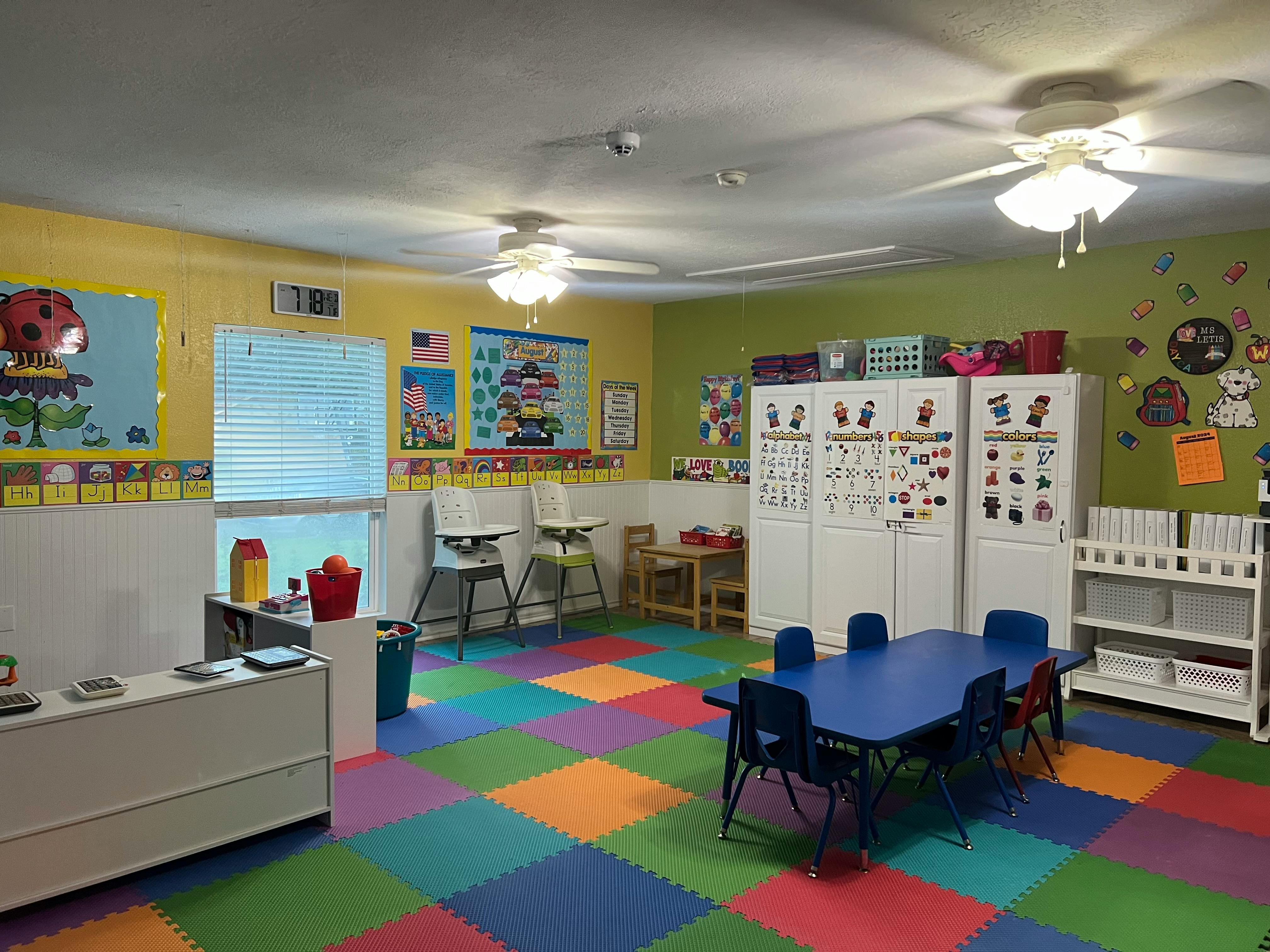 Classroom with colorful floor tiles, small tables, and storage cabinets