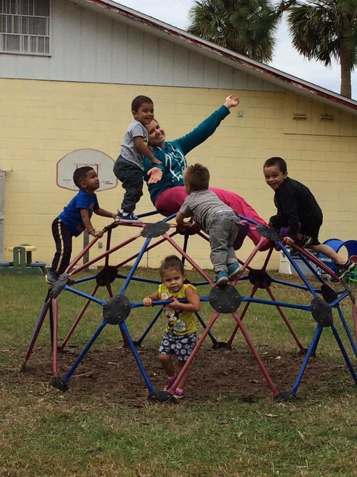 Adult and multiple children climbing on a geodesic dome playground