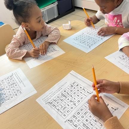 Children working on alphabet maze worksheets in a classroom