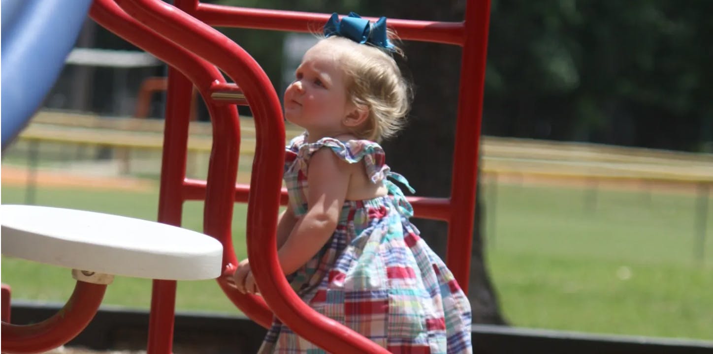 Child in a dress on a playground structure