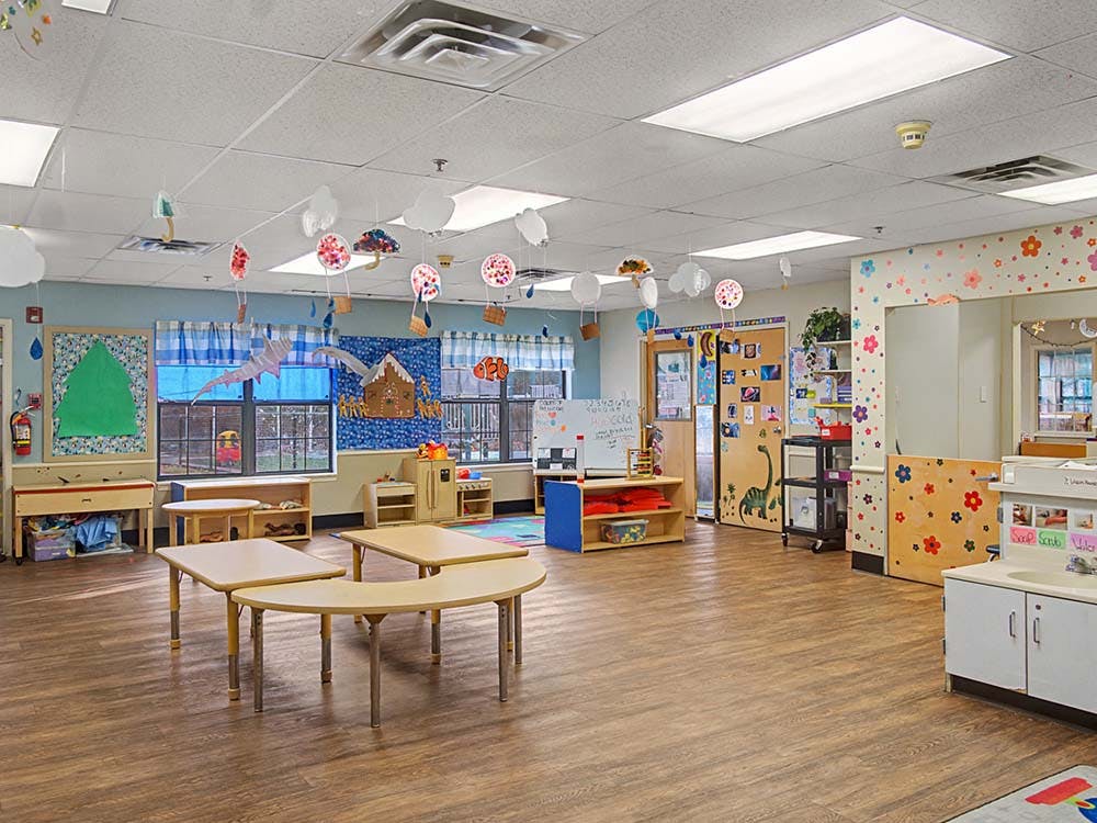 Colorful empty classroom with small tables, chairs, and decorations