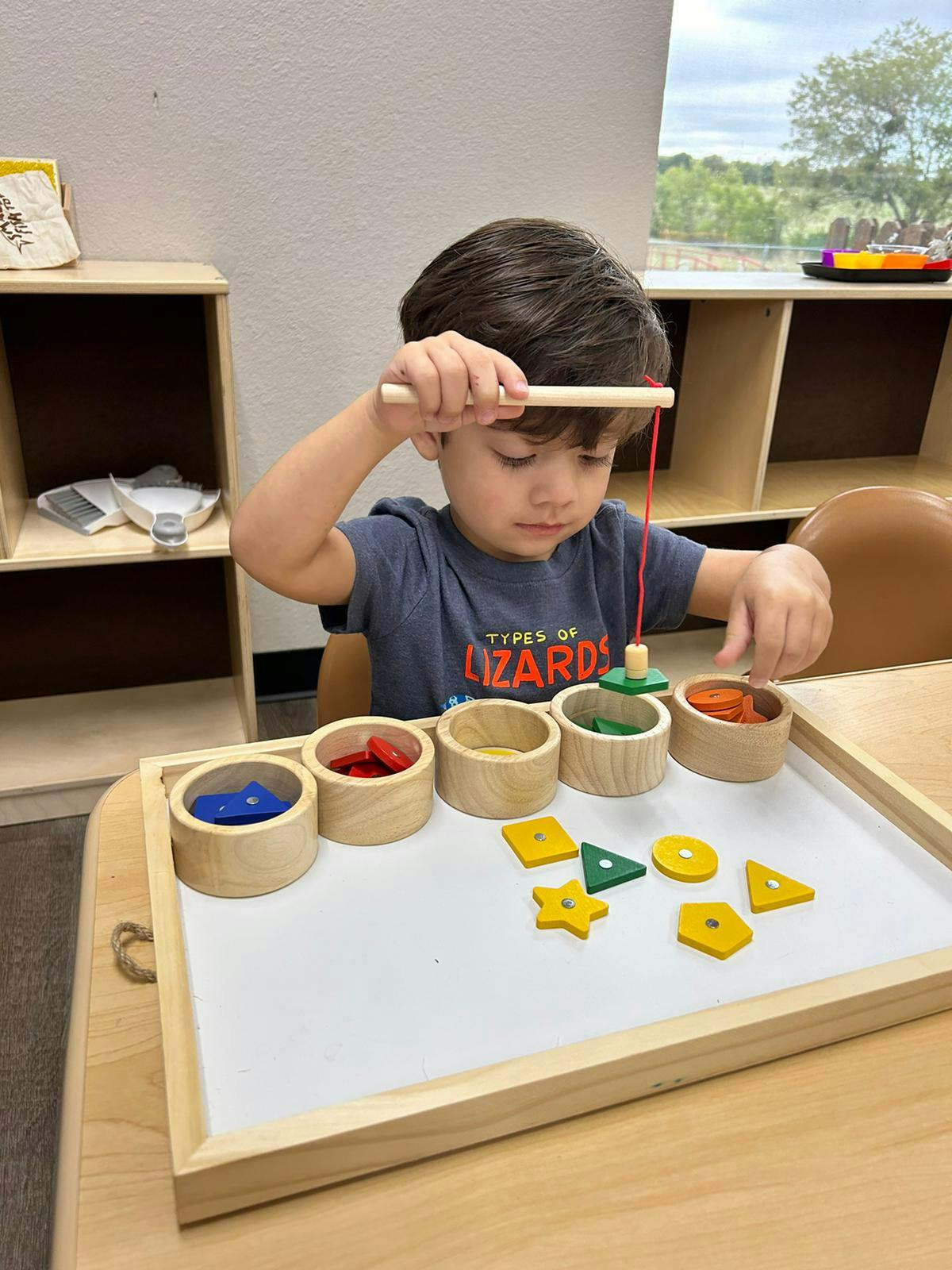 Child playing with a wooden fishing toy and shape sorter