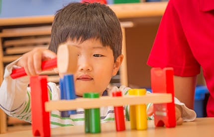 Child playing with a wooden hammer and peg toy