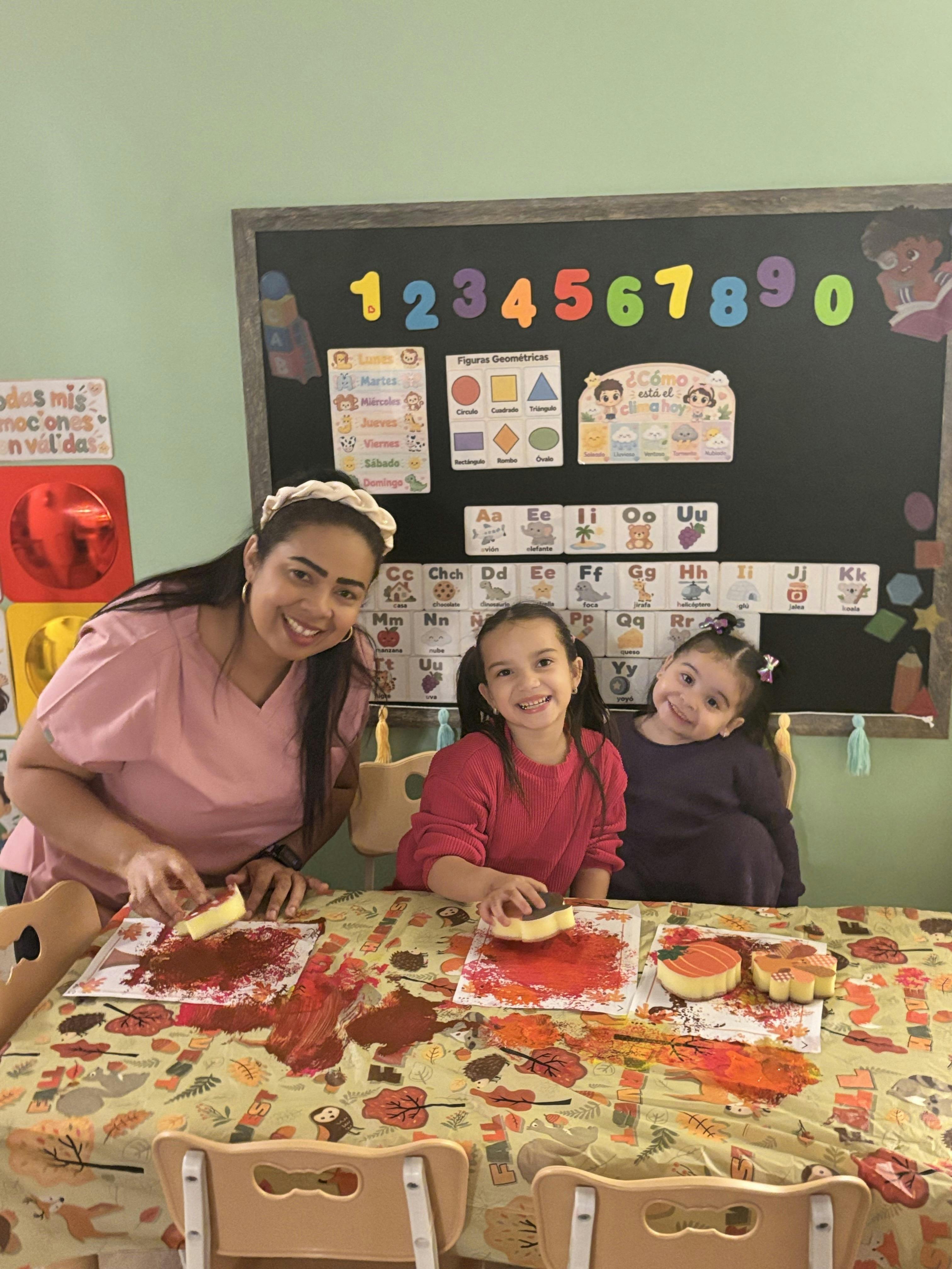 Adult and two children sponge painting in a classroom