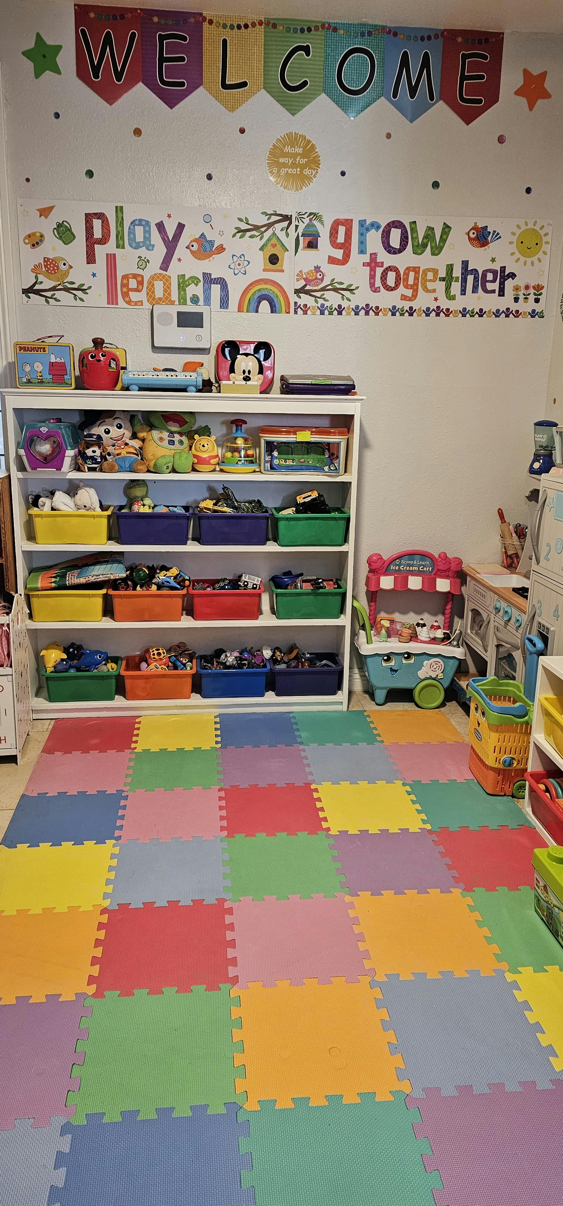 Playroom with colorful floor mats, shelves of toys, and wall decorations
