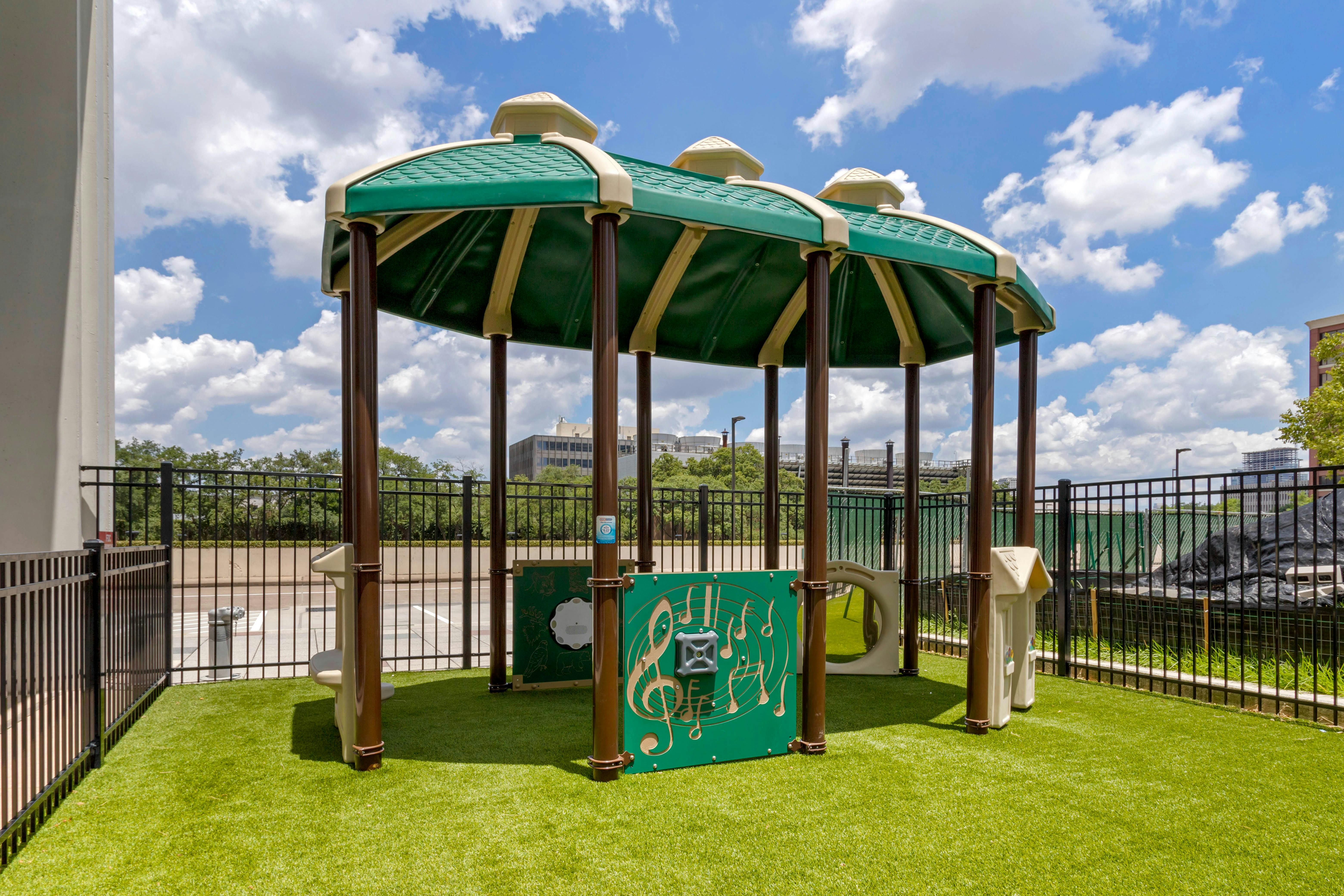 Covered playground area with green turf and musical play panels