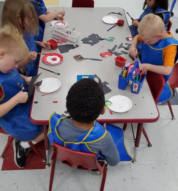 Children in aprons doing crafts at a table