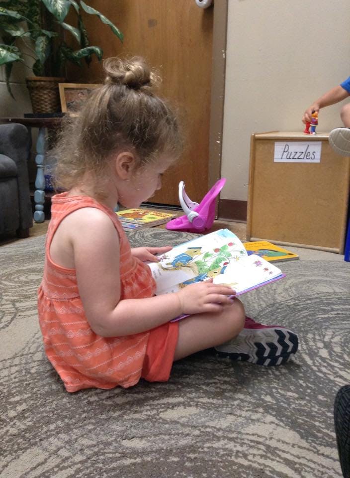 Child sitting on floor reading a book