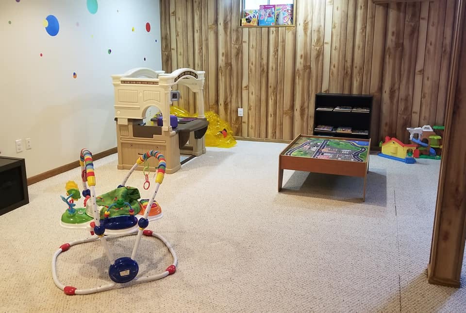 Playroom with baby jumper, playhouse, and game table