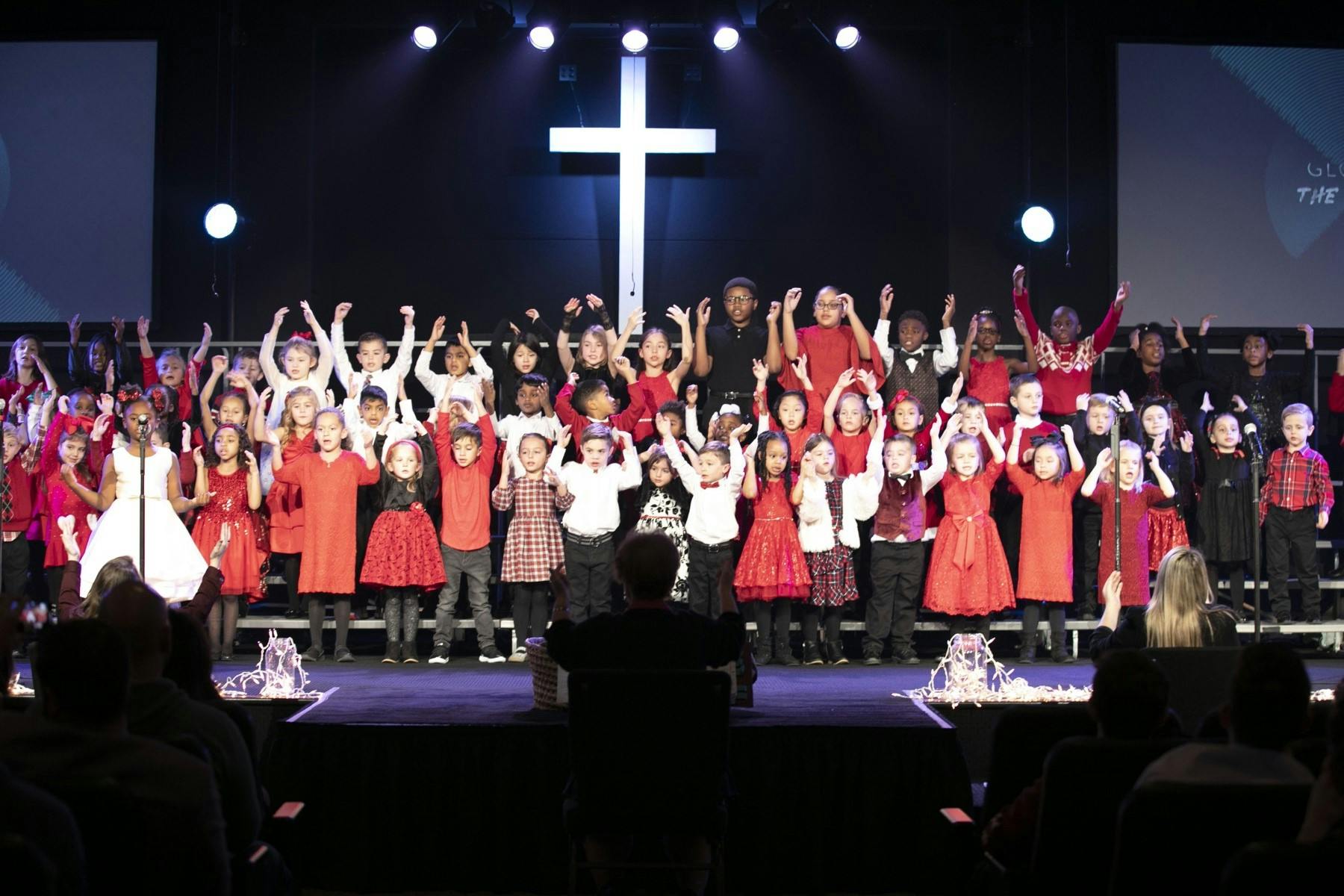 Children on a stage with a large cross in the background