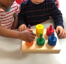 Two children playing with a colorful stacking toy