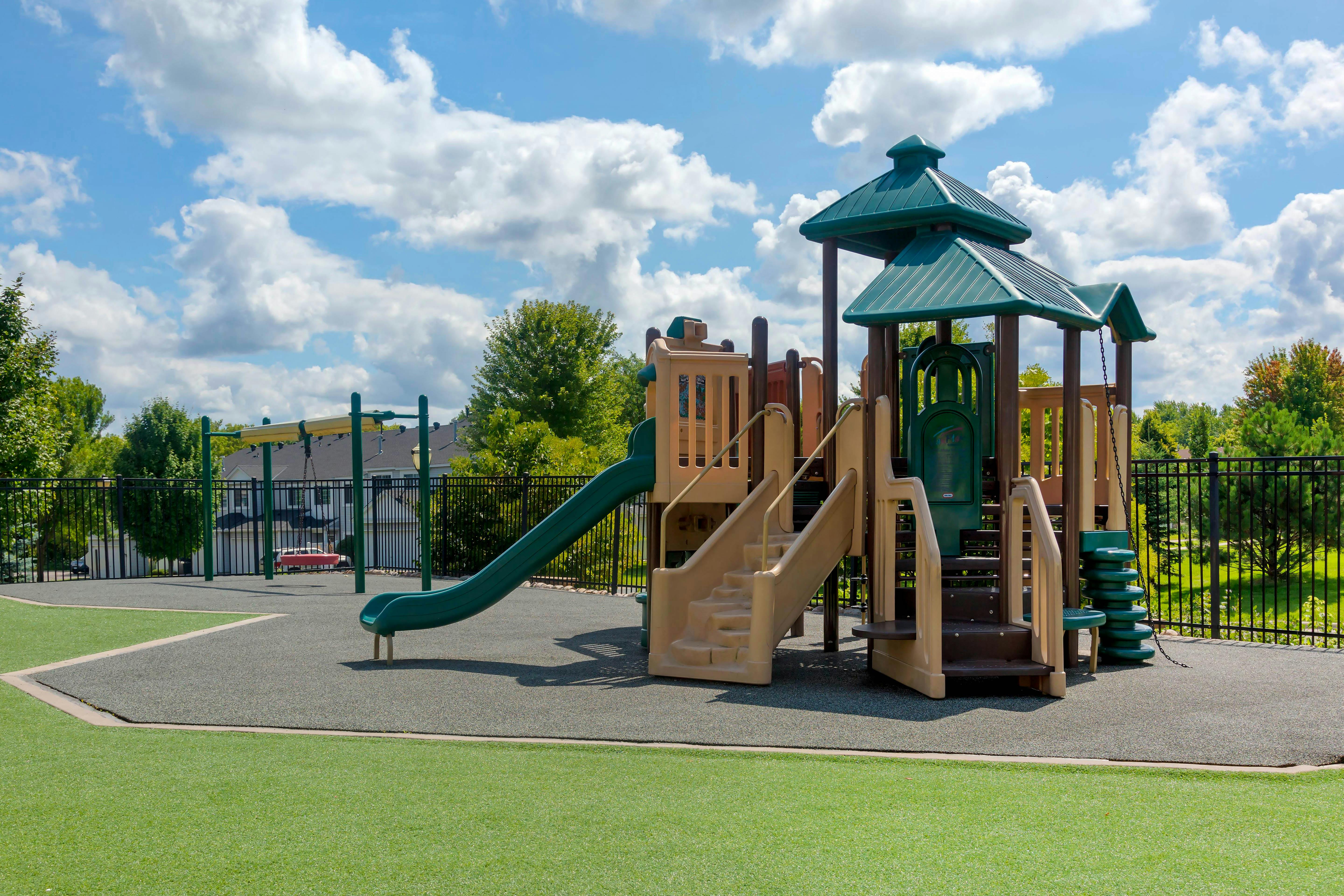 Playground equipment with slides, stairs, and a swing set under a cloudy sky