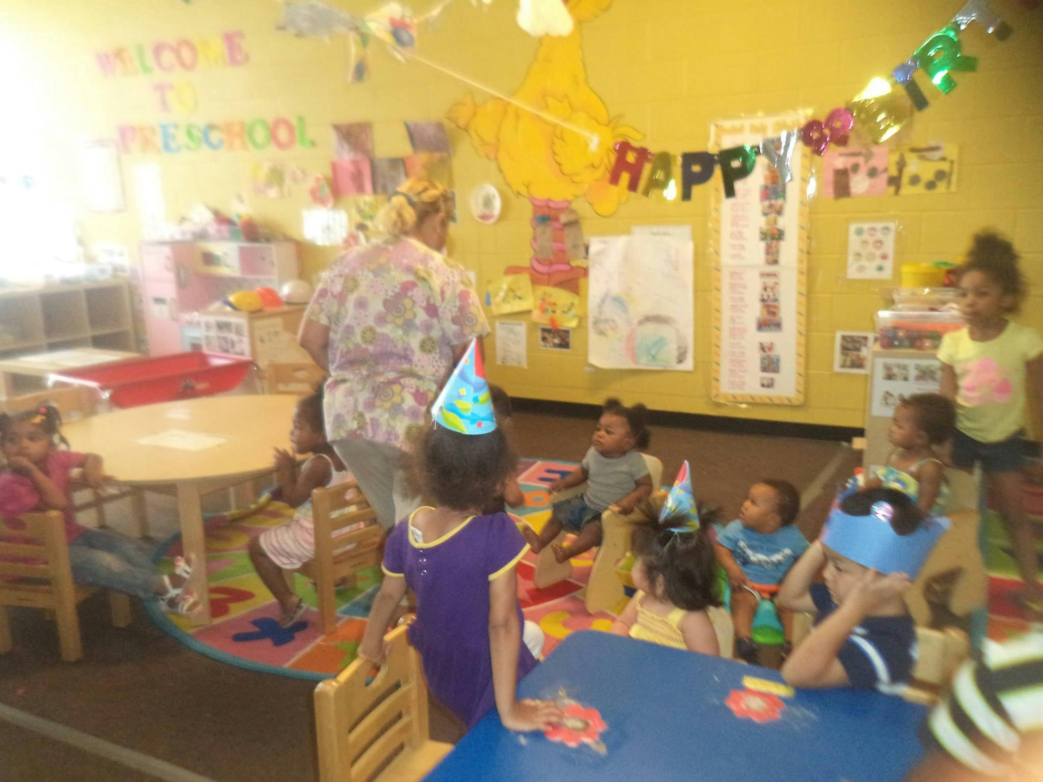 Adult and children in a classroom with party hats