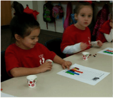 Child at a table with a paper and small cups