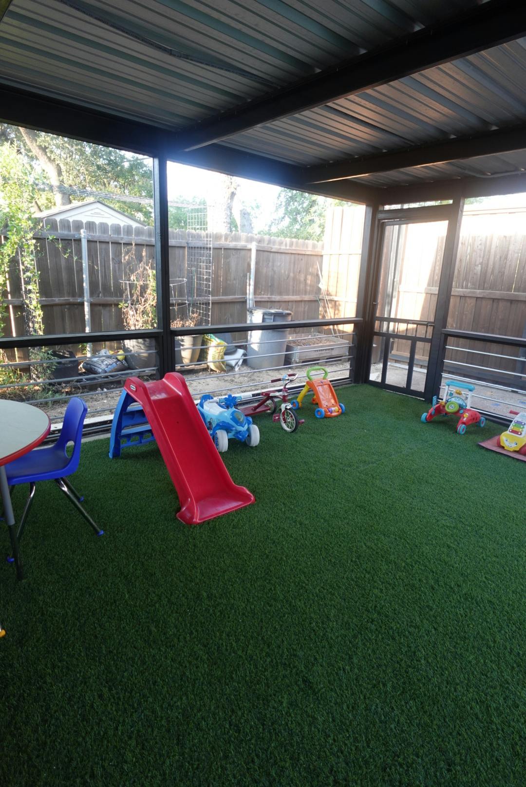 Play area with artificial grass, a red slide, and various toys