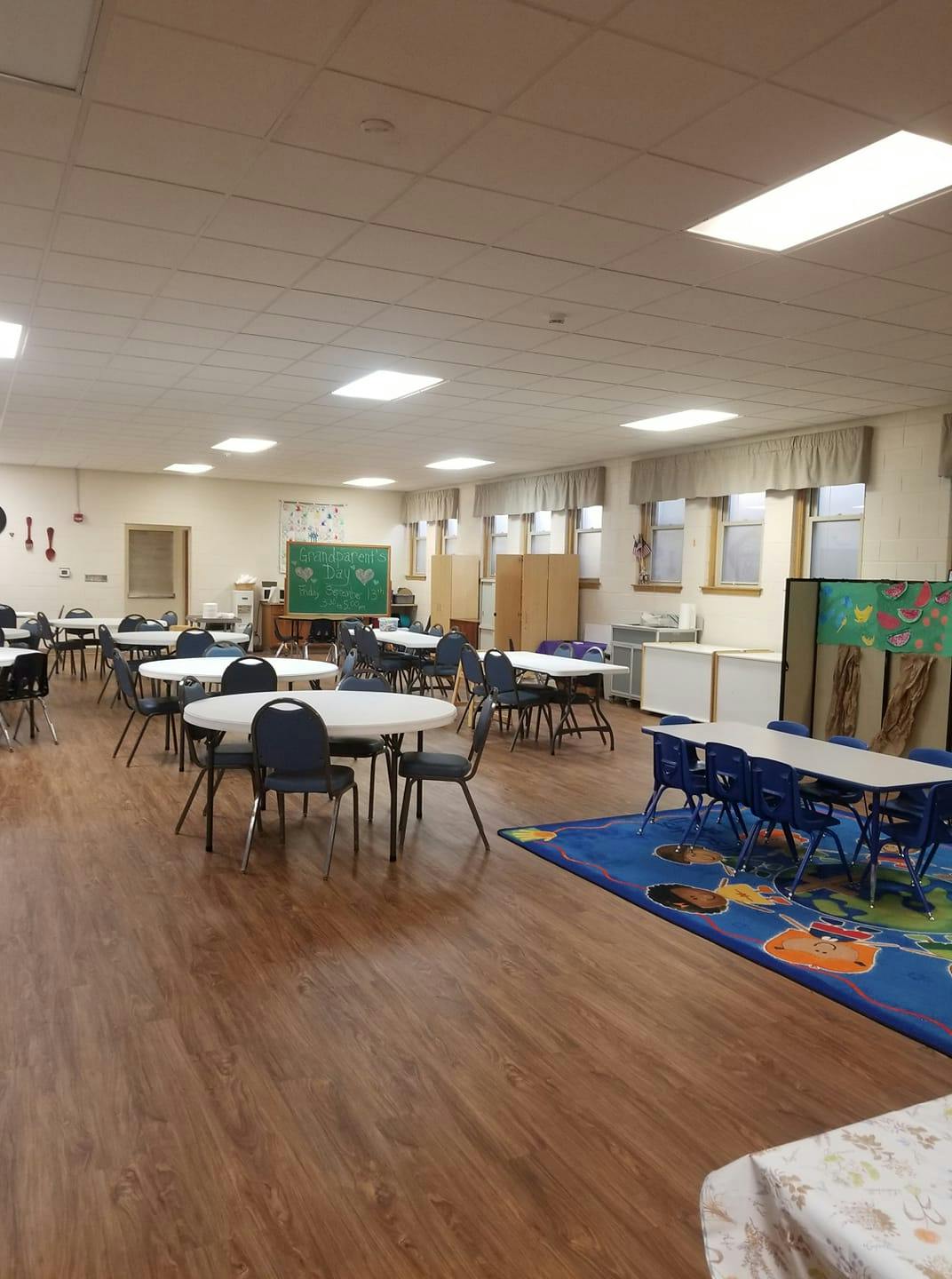Room with multiple tables and chairs, some with a blue rug