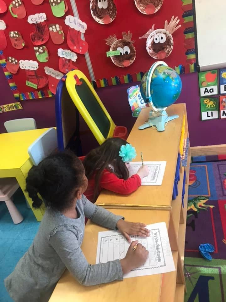 Two children writing at desks in a classroom