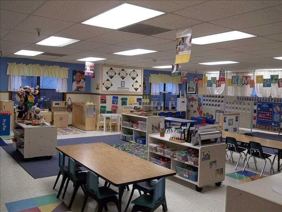 Classroom with tables, chairs, shelving units, and windows