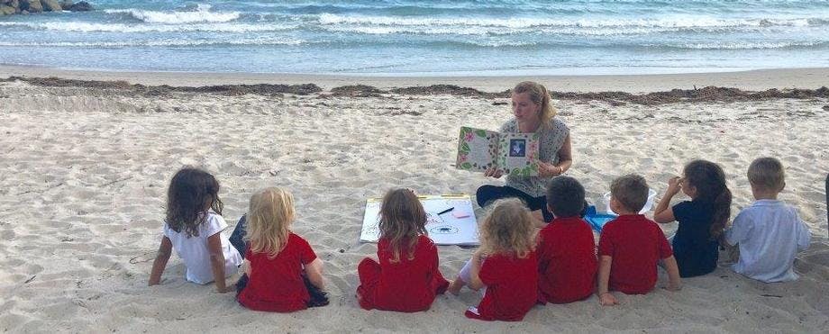 Person reading to children on a beach