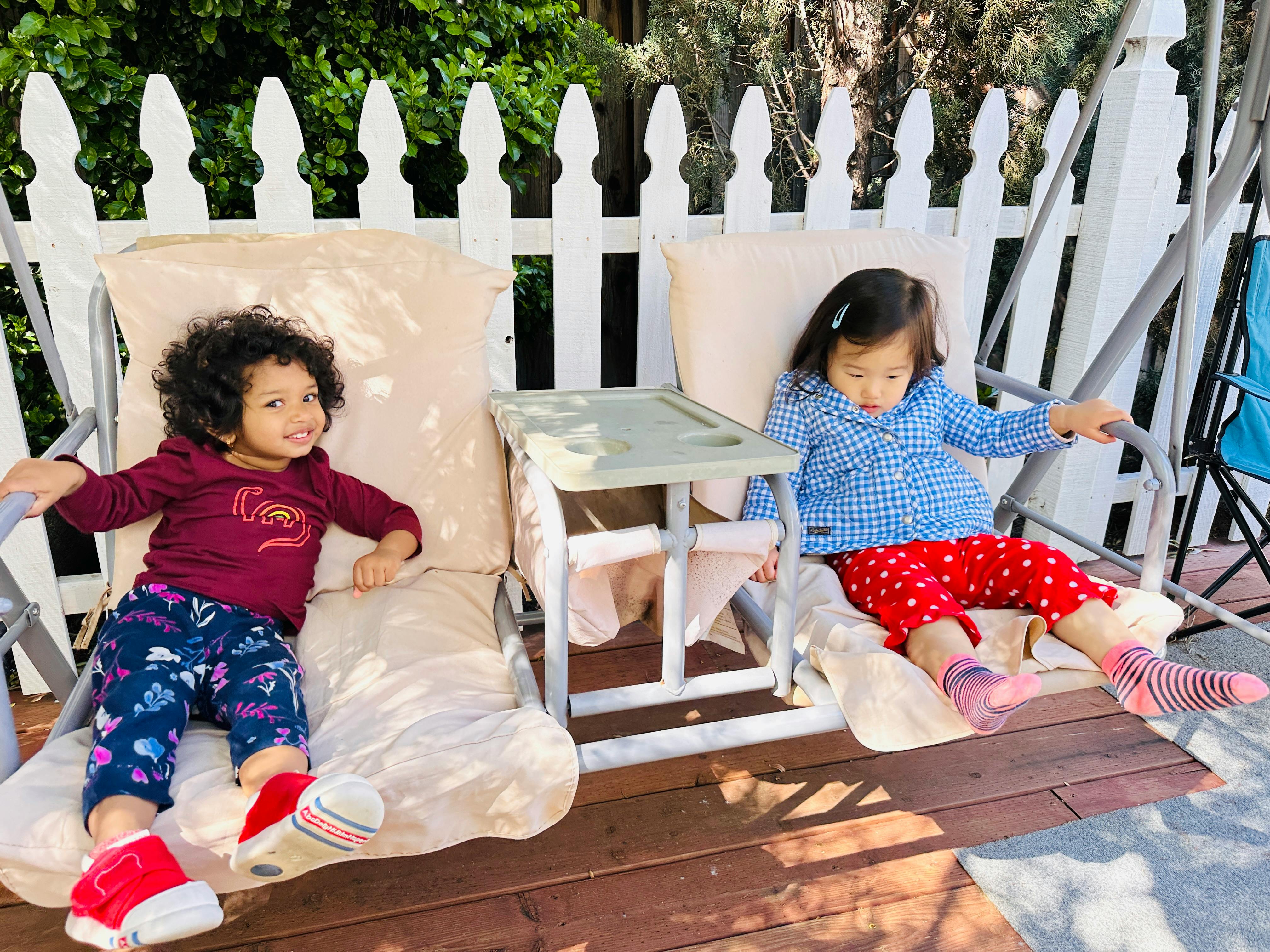 Two children sitting on a porch swing, one looking at the camera