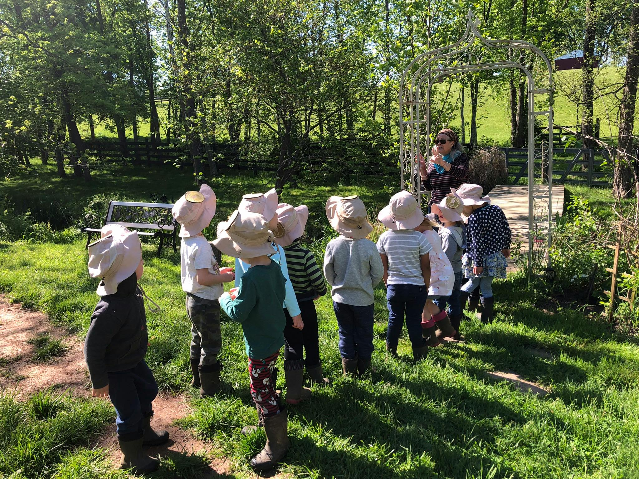 Person speaking to a group of children wearing hats outdoors