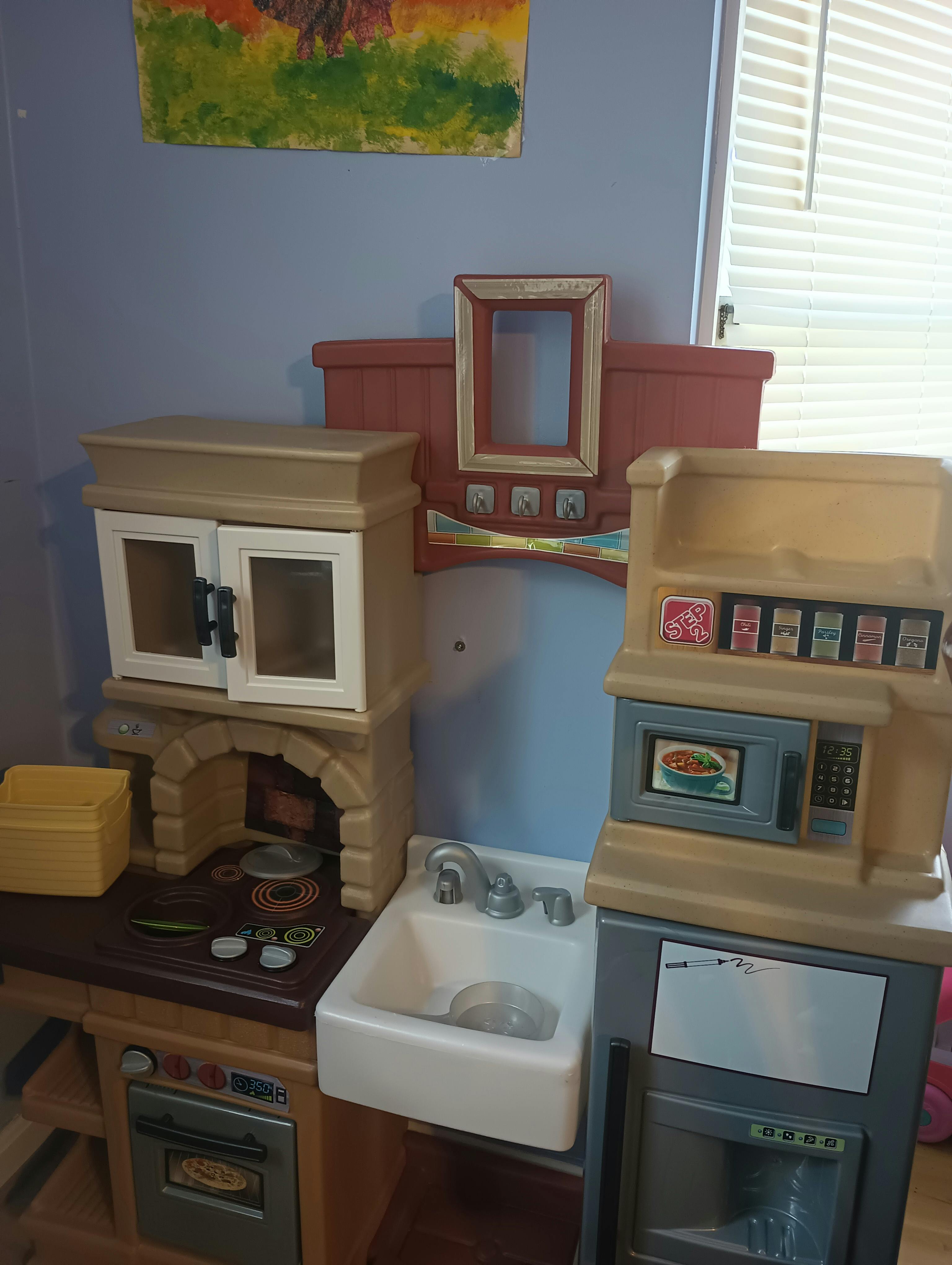 A toy kitchen with an oven, microwave, and sink