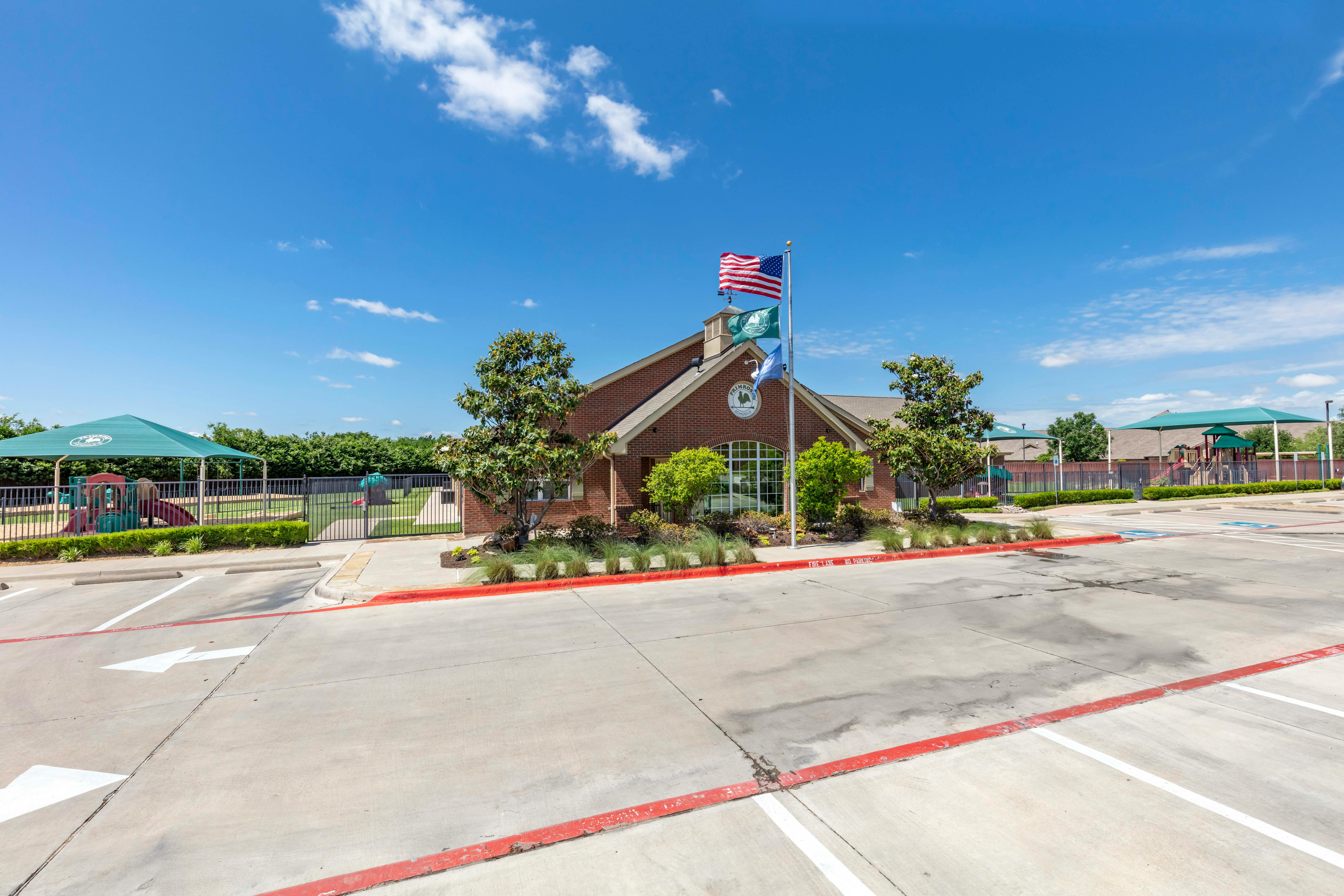 Brick building with a parking lot and playground with green shade structures
