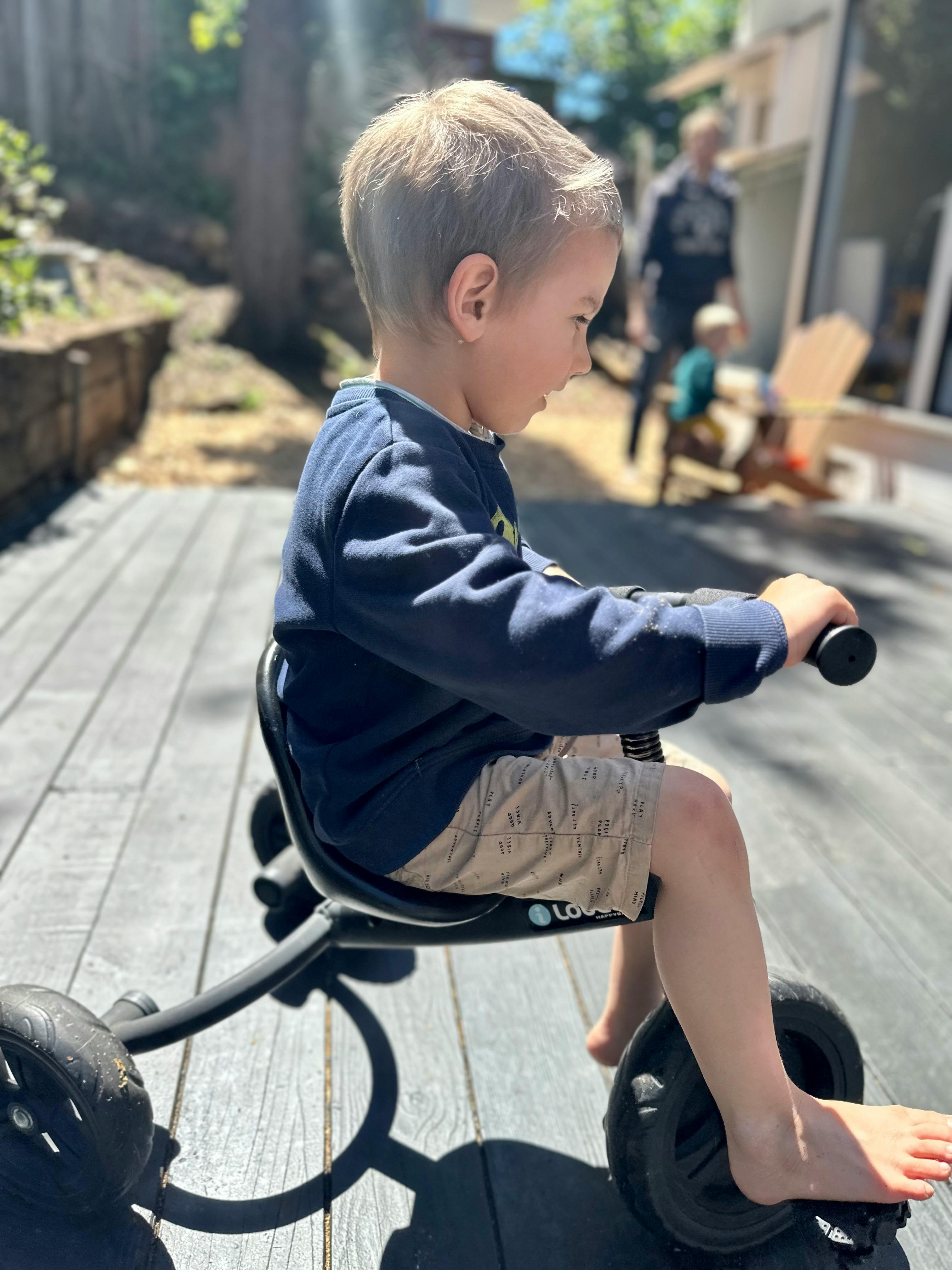 Child riding a tricycle on a wooden deck