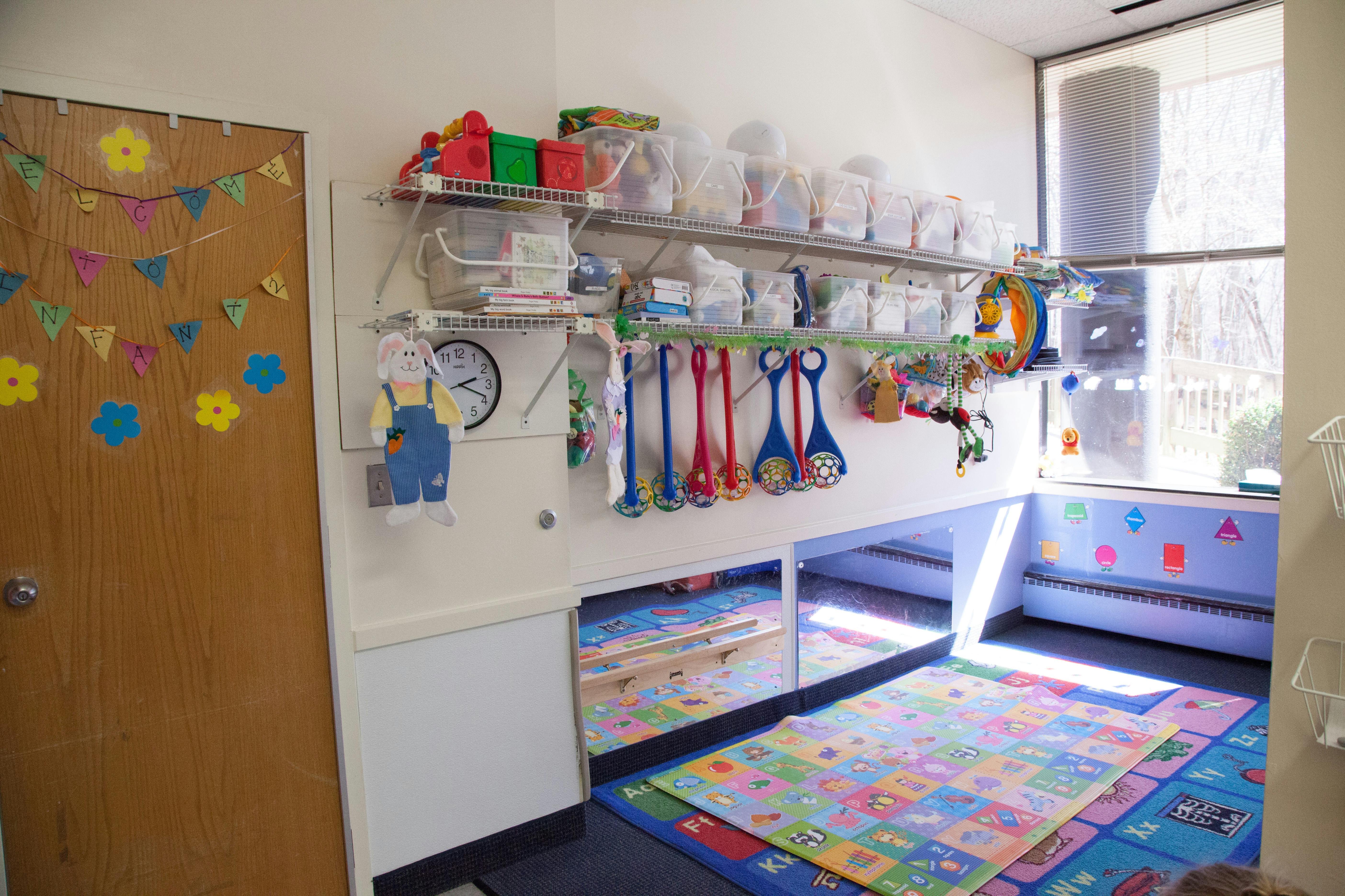 Playroom with shelves of toys, mirrors, and colorful floor mats