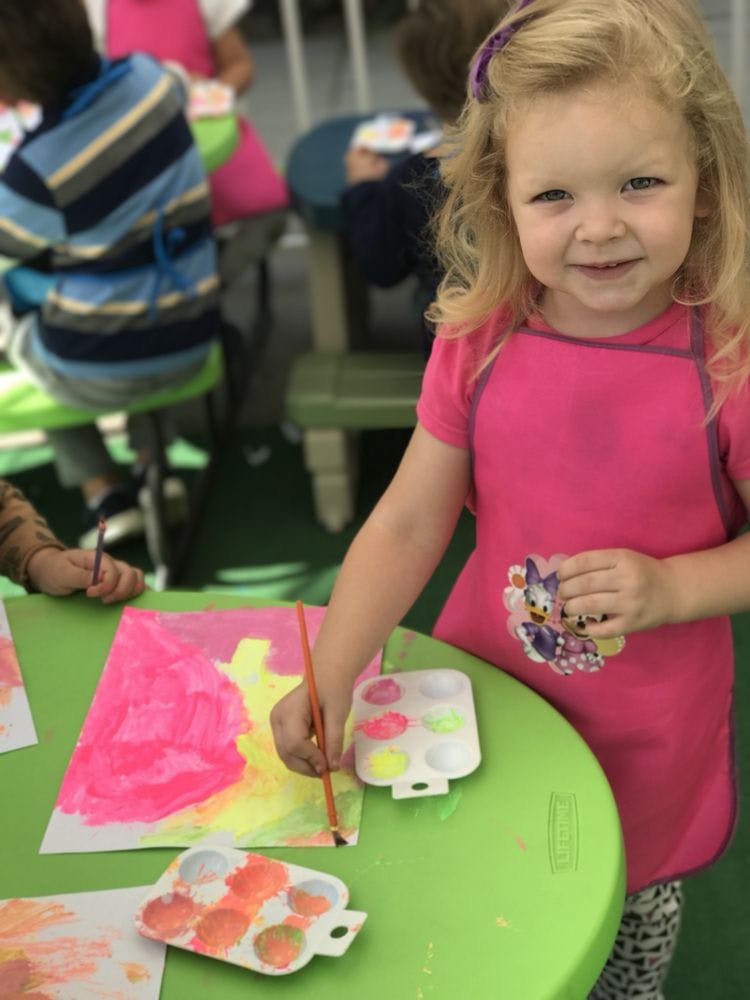 Child painting at a green table