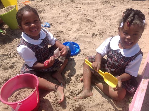 Two children playing in sand with shovels and buckets