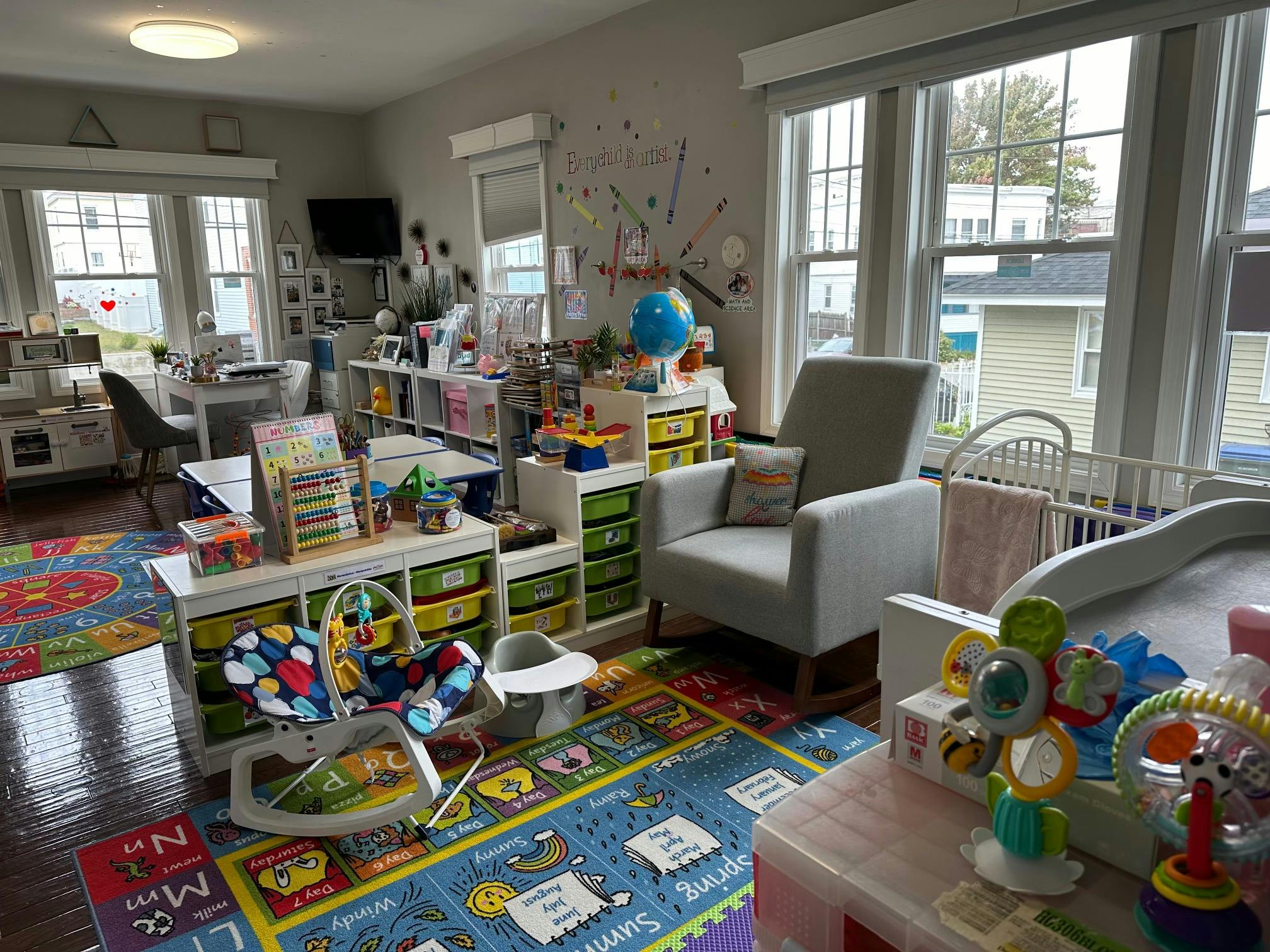 Brightly colored playroom with educational rugs, toys, and a rocking chair