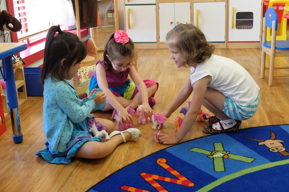 Three children playing with toys on the floor