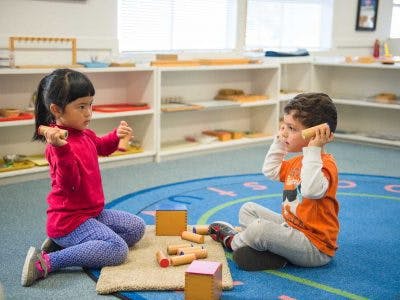 Two children playing with wooden blocks in a classroom
