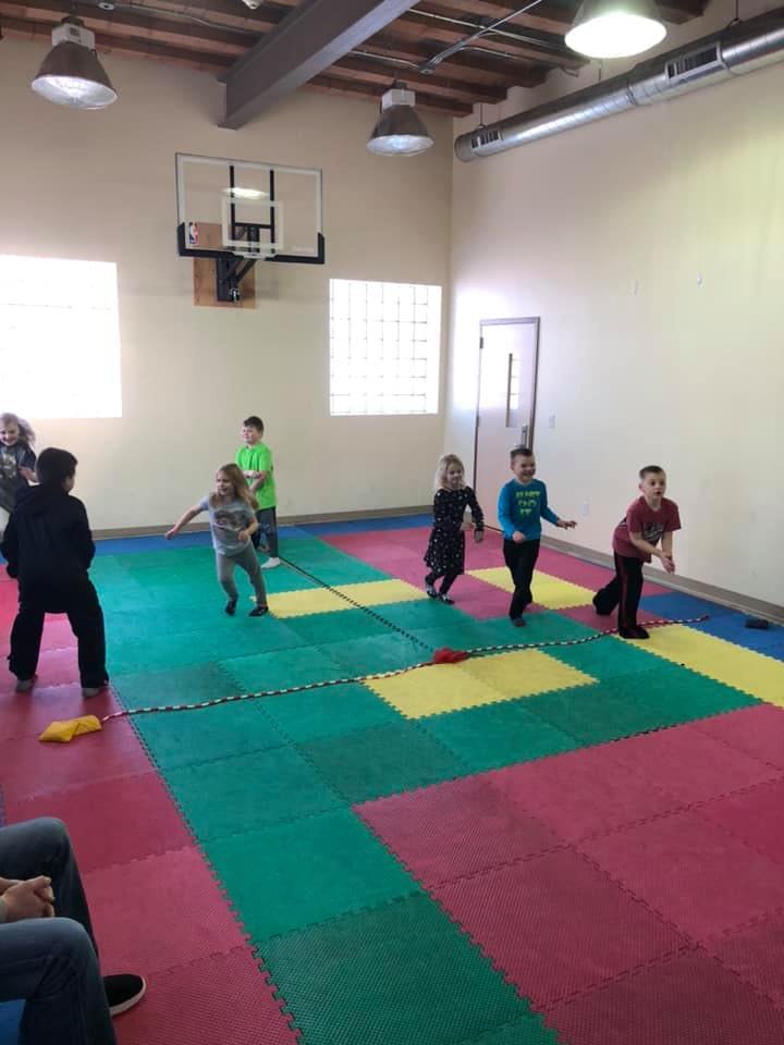 Children playing on a colorful mat in a gym