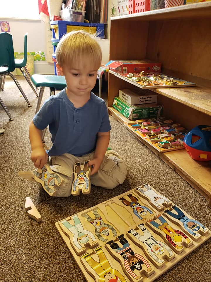 Child playing with a wooden puzzle on the floor