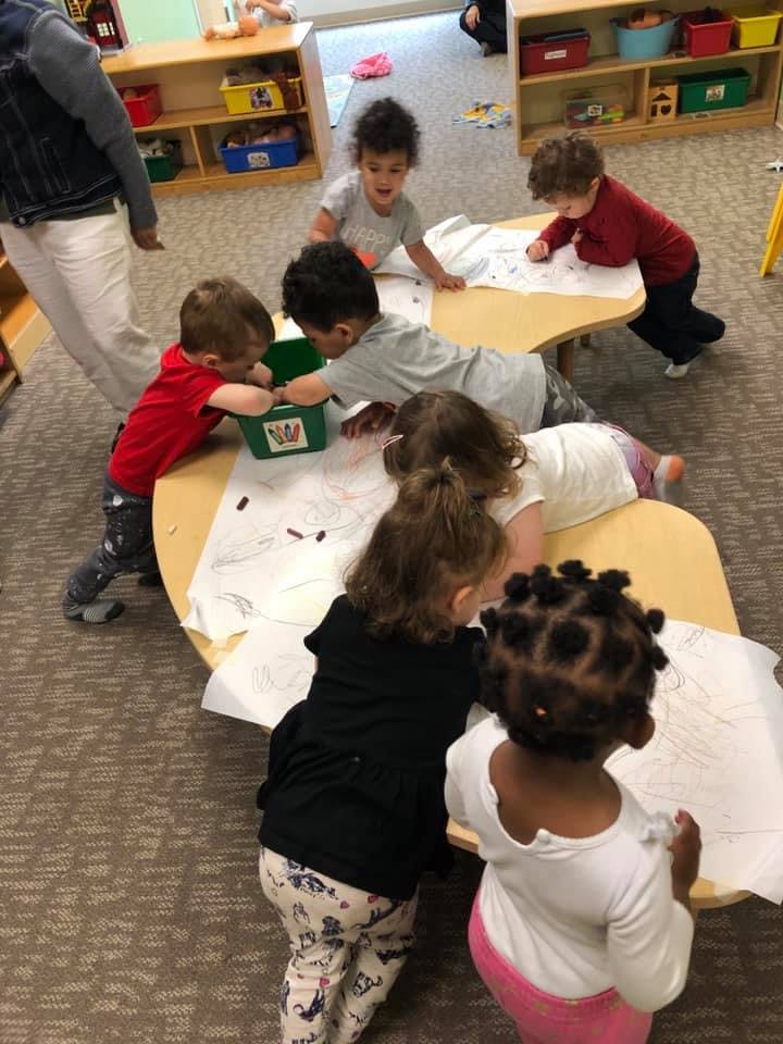 Children gathered around tables in a classroom