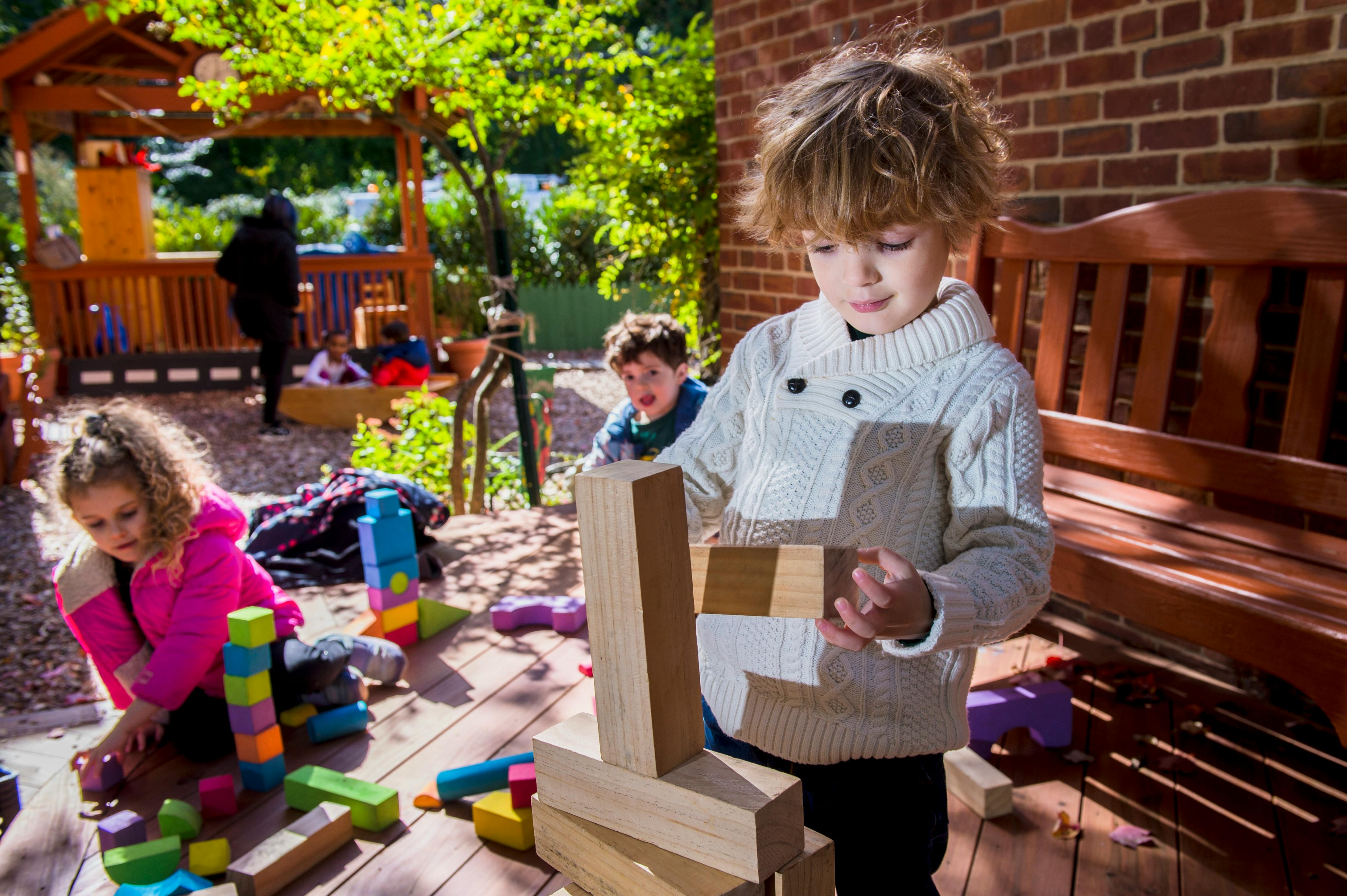 Child building with wooden blocks outdoors