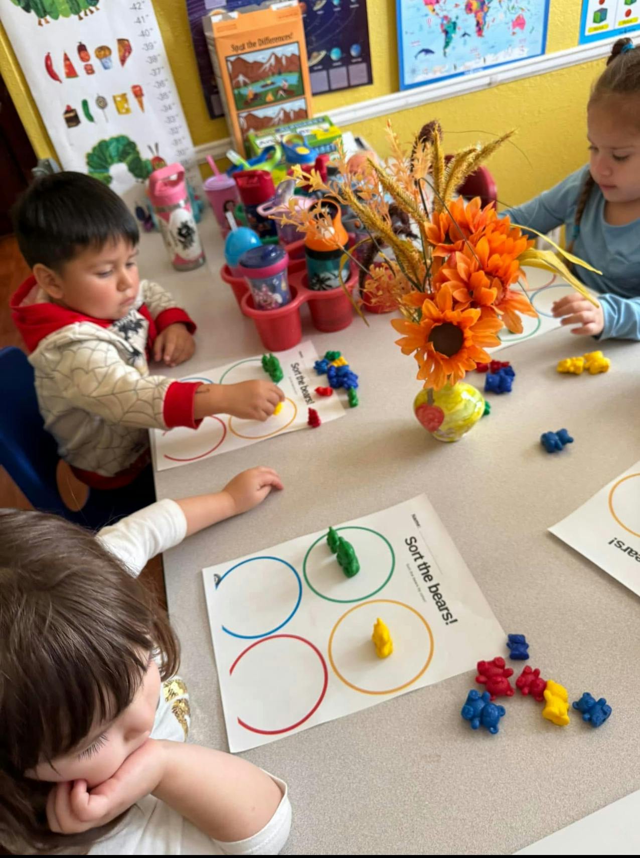 Children sorting colorful bear counters into circles on a worksheet