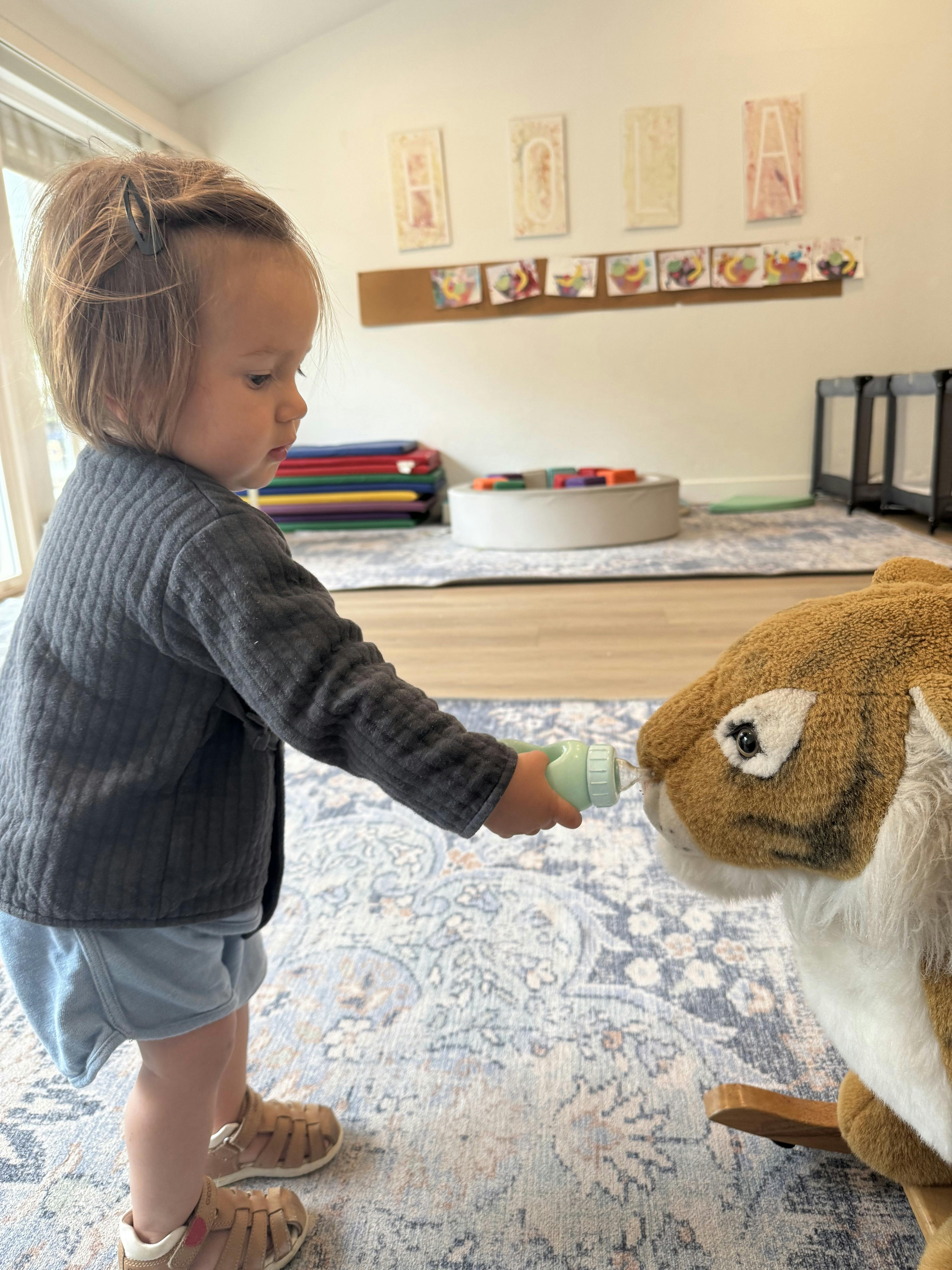 Child feeding a toy rabbit with a bottle