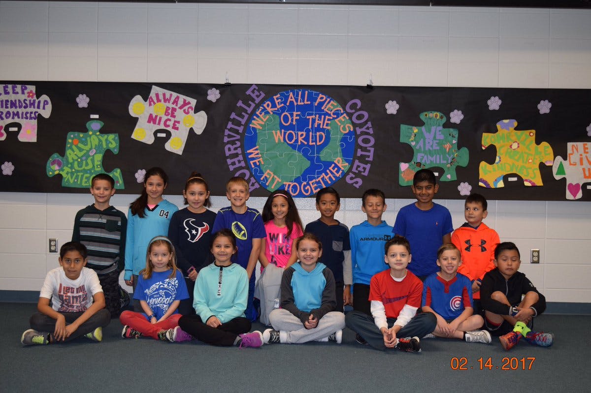 Group of children and teens posing in front of a bulletin board