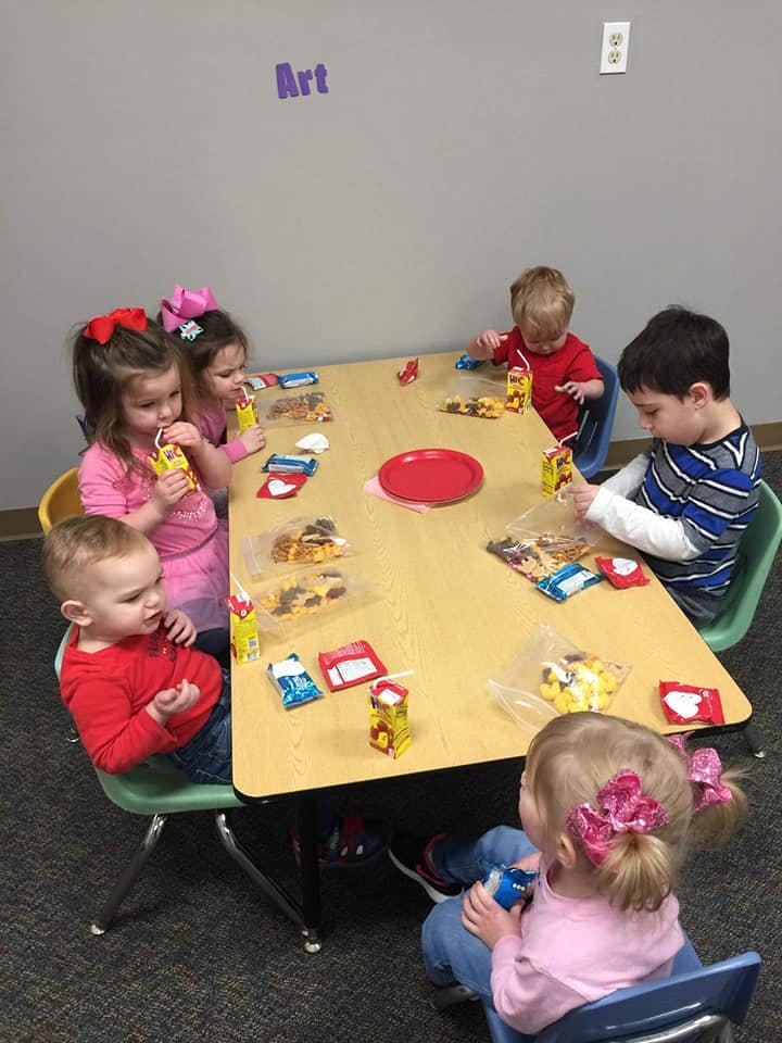 Children sitting at a table with snacks and juice boxes