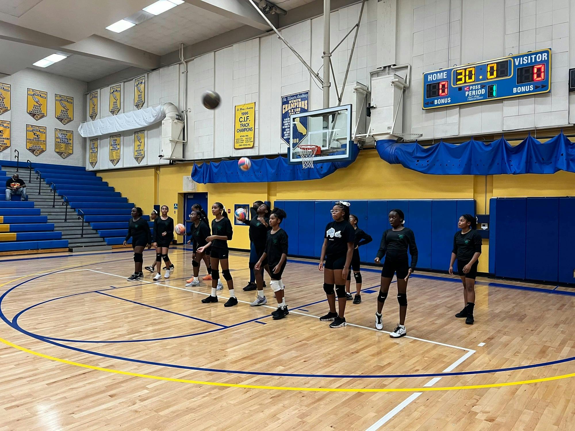 Children playing volleyball on a gymnasium court