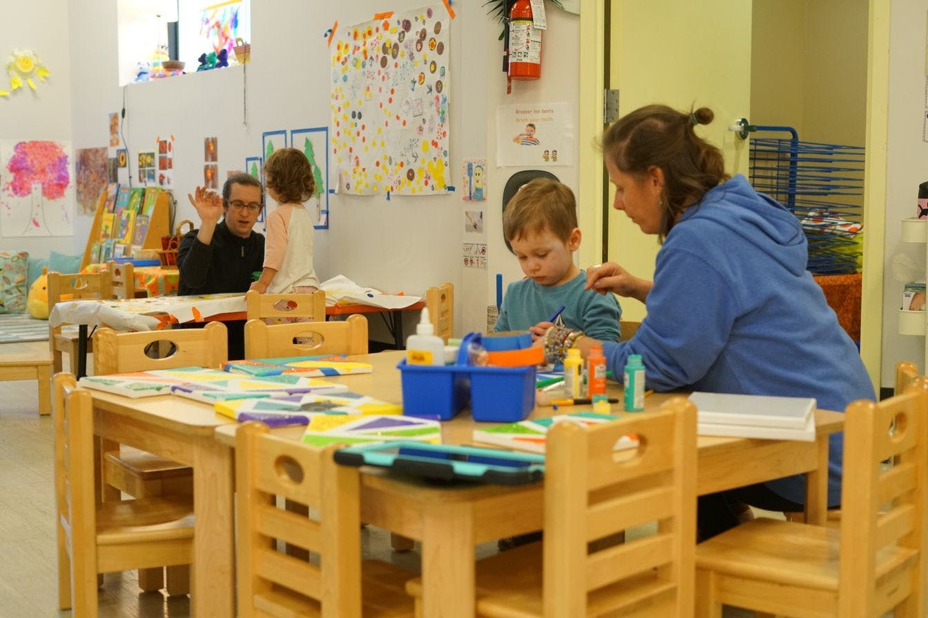 Adults and children engaged in an art activity in a classroom setting